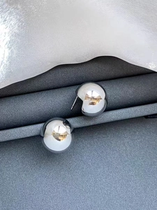 Macro shot of minimalist silver polished spherical earrings with high-gloss metallic finish