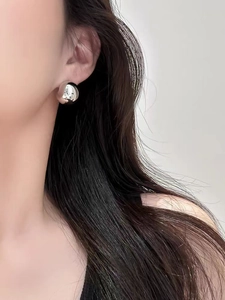 Close-up of a model wearing minimalist silver ball earrings with polished mirror finish