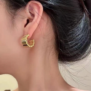 Chic gold-plated C-shaped hoop earrings with vertical ribbed texture on a female model
