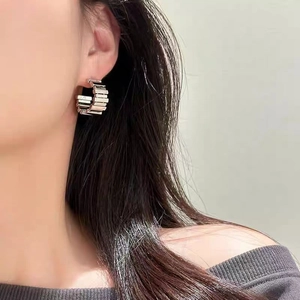 Modern geometric C-shaped hoop earrings with layered step pattern in polished silver metal