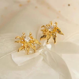 Vintage gold flower stud earrings with sparkling cubic zirconia on white satin bow base