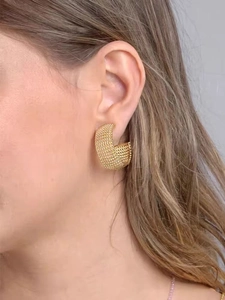 Gros plan de créoles dorées en C avec une texture perlée portée par un mannequin