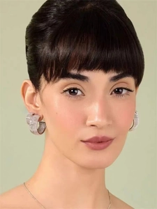 Détail de créoles argentées en C serties de zircons cubiques portées par un mannequin