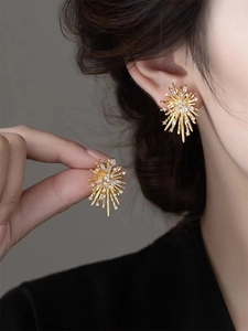 Macro shot of gold firework stud earrings with sparkling cubic zirconia on model ear