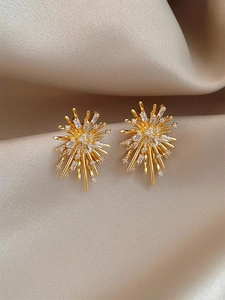 Macro shot of firework zircon earrings on elegant champagne silk fabric background
