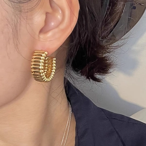 Orecchini a cerchio dorati a forma di C con texture a costine indossati da una modella