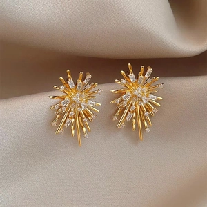 Elegant gold fireworks stud earrings with sparkling cubic zirconia on champagne silk