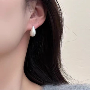 Gros plan sur une boucle d'oreille goutte en argent avec finition mate brossée