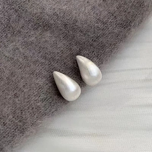 Gros plan de boucles d'oreilles goutte d'argent avec finition en métal brossé