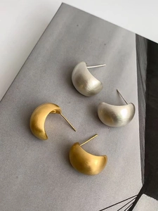 Makro-Detail minimalistischer C-förmig gebürsteter Metallstecker in Gold und Silber