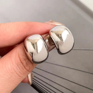 Close-up of chunky silver bean earrings with a high-polished mirror finish texture