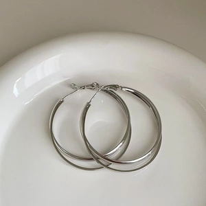 Close-up of double-layered silver hoop earrings displayed on white ceramic tray