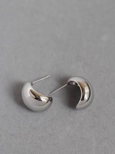 Close-up of glossy silver dome stud earrings with a polished metallic mirror finish