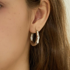 Minimalistische silberne Creolen mit welliger Struktur, von einem Model getragen