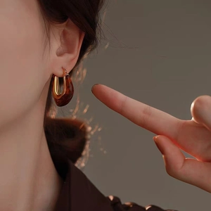 U-shaped earrings with gold metal and amber resin on a model in vintage style
