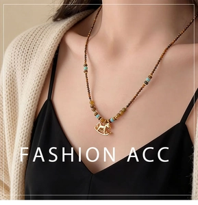Detail of beaded necklace with gold rocking horse pendant and brown tiger eye stones