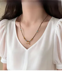 Golden rocking horse pendant on a brown and blue beaded chain necklace worn by a model