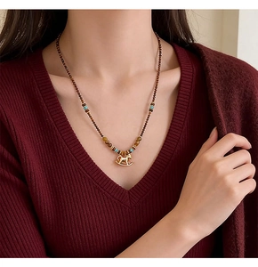 Detail of golden rocking horse pendant on a brown beaded necklace with blue accents