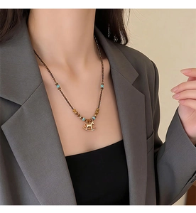 Close-up of golden rocking horse pendant necklace on model wearing grey suit