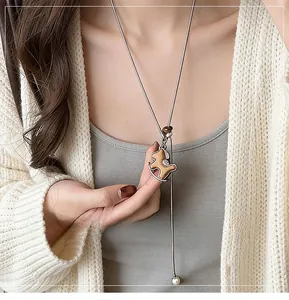 Dettaglio del ciondolo a cavallo in legno con perla su una collana lunga da maglione