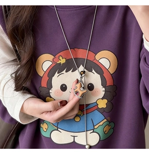 Dettaglio della collana con ciondolo a cucciolo marrone indossata su un maglione viola