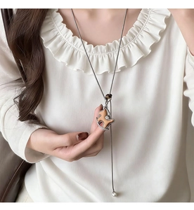 Dettaglio della collana con pendente a cavallo a dondolo in legno con perla e metallo