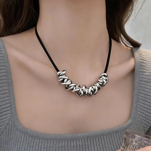 Close-up of a black cord necklace featuring irregular silver metal knots on a grey sweater