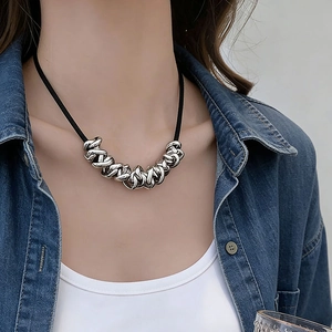 Modern black rope necklace with intertwined irregular silver rings on female model