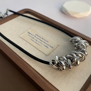 Minimalist black cord necklace with interlocking silver rings on a premium display