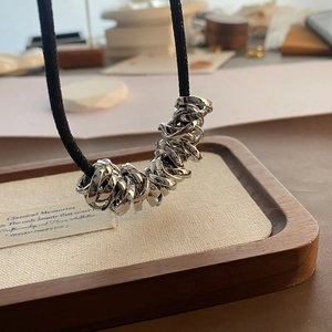 Macro view of silver irregular intertwined rings pendant with minimalist black cord