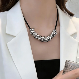 Close-up of industrial silver interlocking rings on a black cord worn with a blazer