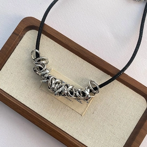 Detail of minimalist black cord necklace with irregular silver metallic rings on a tray