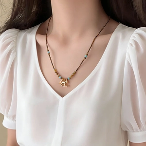 Golden rocking horse pendant necklace with brown and blue beads shown on model
