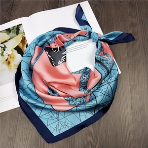 Artistic silk-like square scarf featuring geometric patterns on a wooden desk