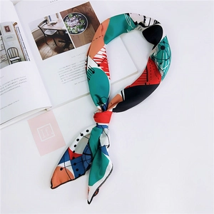 Foulard in seta con motivi geometrici astratti verdi e rossi su scrivania bianca