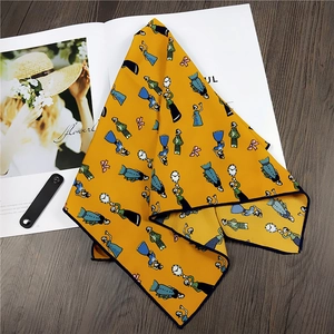 Yellow vintage cartoon print square silk scarf with navy rolled edges on a wood background