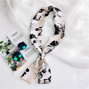 Detailed close-up of a long silk scarf featuring black ink floral prints on beige fabric
