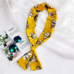 Close-up of yellow floral twilly silk scarf with hand-drawn lotus patterns and sunglasses