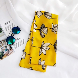 Detail view of yellow floral silk scarf with hand-drawn leaf pattern and sunglasses