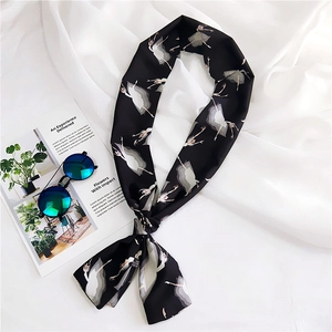 Detail of a black silk twilly scarf featuring white ballerina prints and soft texture