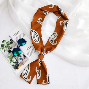 Detail of soft orange paisley silk scarf with glossy texture and elegant knotted style