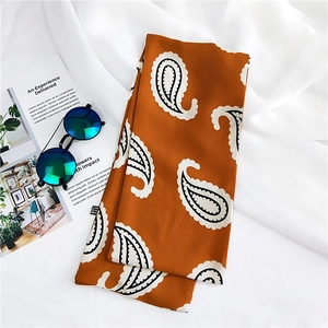 Detail of paisley silk scarf in caramel and black with chic sunglasses and book