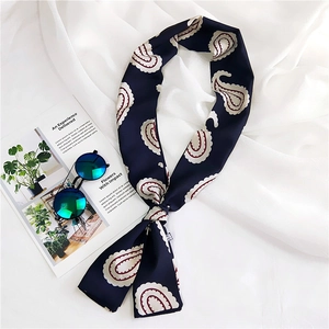 Detail of navy blue paisley silk scarf styled with sunglasses on white fabric