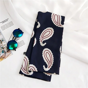 Detail of navy blue paisley silk scarf styled with sunglasses and a magazine