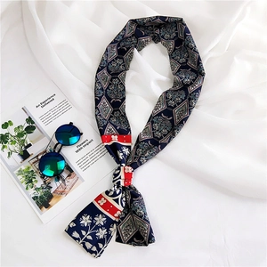 Detail of navy blue patterned narrow silk scarf displayed with sunglasses on white fabric