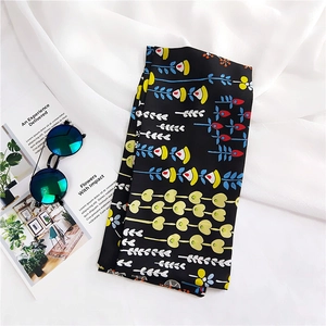 Close-up of a long black silk scarf with colorful floral patterns and retro sunglasses