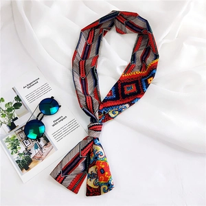 Detail of colorful geometric pattern long silk scarf tied elegantly on white silk fabric
