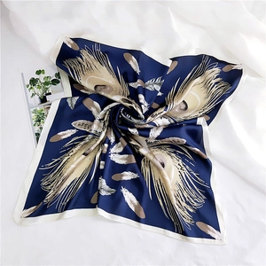 Detail of silk square scarf showing intricate peacock feather patterns on deep blue fabric