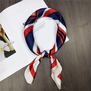 Detail of red and navy geometric stripe silk scarf tied elegantly on a white magazine