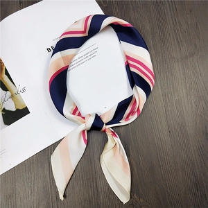 Navy and pink striped silk scarf knotted on a wooden surface with a white magazine